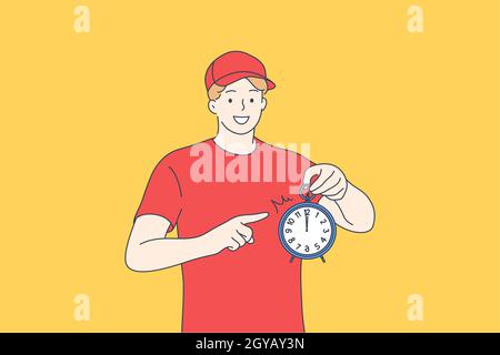 Courier delivery service, being in time concept. Happy young man in red working uniform standing and pointing at alarm clock meaning delivering parcel Stock Photo