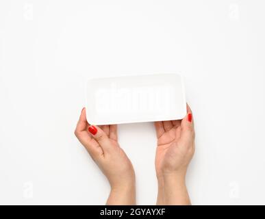 Female hands hold an empty rectangular disposable plastic container on a white background, top view Stock Photo