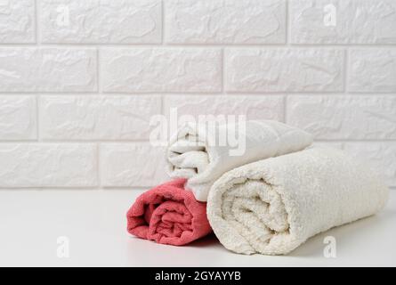 clean white rolled terry towels on white shelf, bath interior Stock Photo
