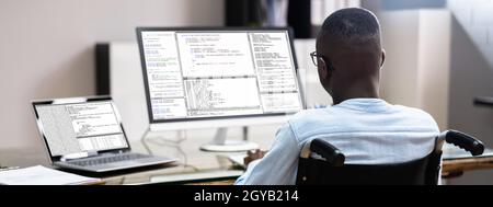 African American In Wheelchair Using Computer. Handicapped Developer Coder Stock Photo