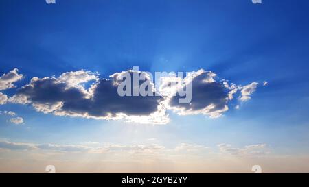 Beautiful strangely shaped clouds with the sun behind them. Awesome sun rays. Stock Photo