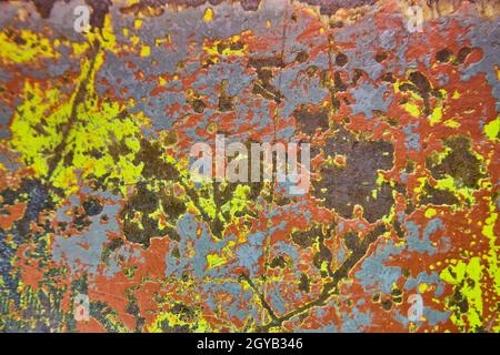 Abstract shot of chipped gray paint that reveals blues, yellows and reds Stock Photo