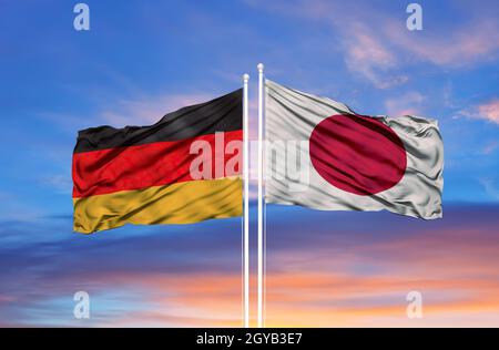 Japan and Germany two flags on flagpoles and blue cloudy sky Stock Photo