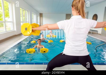 Teacher or coach in water gymnastics class showing the exercises Stock Photo