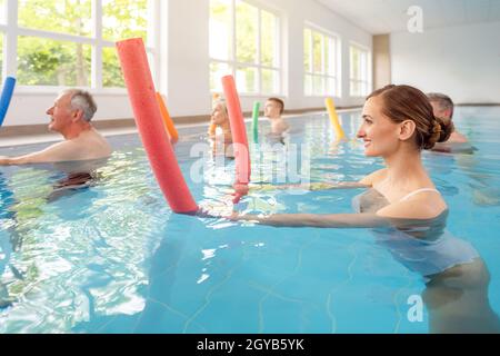 Patients during remobilization in a health center doing aquarobics in the water of a pool Stock Photo