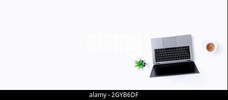 Top view above on gray thin isolated laptop notebook, white cup of espresso coffee, green flowerpot with houseplant on the white background. Banner wi Stock Photo