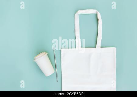 Eco white craft paper bag, metal drink straw, coffee cup on green background flat lay with copy space empty advertising area. Mock up for delivery ser Stock Photo