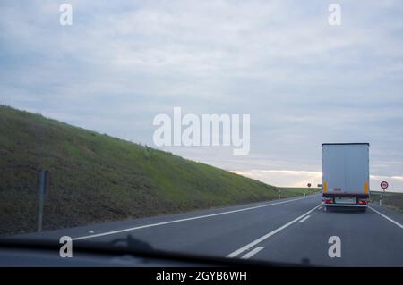 Driving behind  refrigerator truck or chiller lorry at sunset. View from the inside of the car Stock Photo
