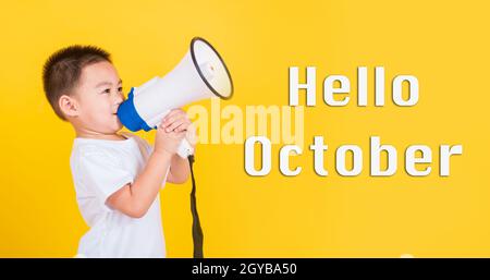 Hello October, Asian Thai happy cute little cheerful child boy holding and shouting or screaming through the megaphone her looking to side, studio sho