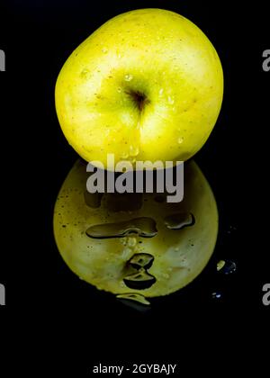 Fruit green apple in drops of water on a black glass background with reflection. Background image. Food photo. Place for text. Apples Golden. Apple ju Stock Photo
