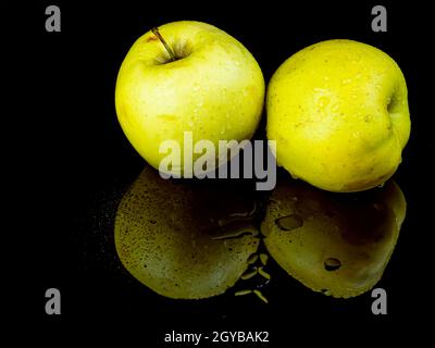Fruit green apple in drops of water on a black glass background with reflection. Background image. Food photo. Place for text. Apples Golden. Apple ju Stock Photo