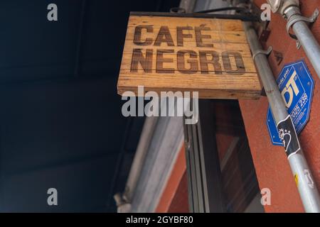 Wooden sign with Spanish text hanging from red wall Stock Photo