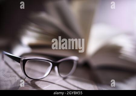 Composition with glasses and open book on the table. Stock Photo