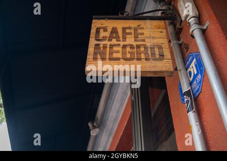 Wooden sign with Spanish text hanging from red wall Stock Photo