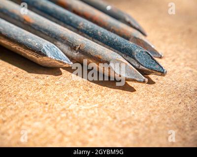 Iron nails on a wooden table macro photo. Nail head. Sharp tip. Joiner's material. Wooden background. Macro photography. Background image. Place for t Stock Photo