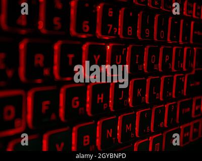 Black computer keyboard with red backlight in the dark. Laptop keyboard. Electronic technology. Background image. Typing. Abstraction. Stock Photo