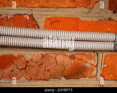 Electrical wiring in plastic corrugation on a brick wall. Electrical wiring. Corrugation for wires. Master electrician. Electrician repairman. Volt. A Stock Photo