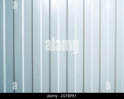 The texture of the striped corrugated metal surface is white. Vertical white stripes. The metal wall is painted white. Background image. Surface textu Stock Photo