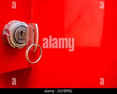 Key in the keyhole on a red background. Car ignition key. Door lock. Open or close the door. Property protection. Safety system. Private property. Ban Stock Photo