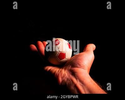 Soccer ball in hand on a black background. Soccer ball. Palms of human hands. Mans hand. Sports Championship. Football tournament. Game team sport. Fo Stock Photo