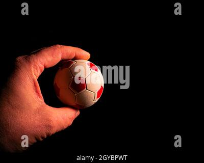 Soccer ball in hand on a black background. Soccer ball. Palms of human hands. Mans hand. Sports Championship. Football tournament. Game team sport. Fo Stock Photo
