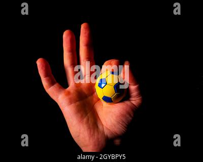 Hand gesture ok with soccer ball on black background. Gesture ok. Mans hand. Sports Championship. Soccer ball. Football tournament. Game team sport. B Stock Photo