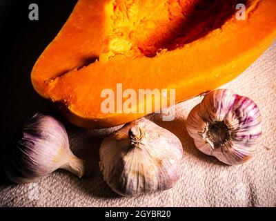 Orange pumpkin and garlic vegetable on a black background. Harvest vegetables. Head of garlic. Halloween orange pumpkin. Halloween holiday. Agricultur Stock Photo