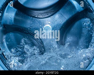 Rotating drum in the washing machine tub with water. Washer. Automatic laundry. Service and repair of equipment. Splashing water. Repair shop. Stainle Stock Photo