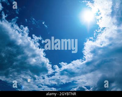 Sun on a blue sky with white clouds. Sun rays. Blue sky. White cloud. Cloudy horizon. Natural landscape. Space. Background image. Heavenly beauty. Sum Stock Photo