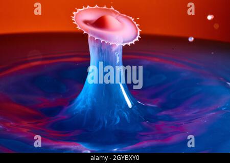 Splash of misty blue water with saw type burst and red and purple background Stock Photo