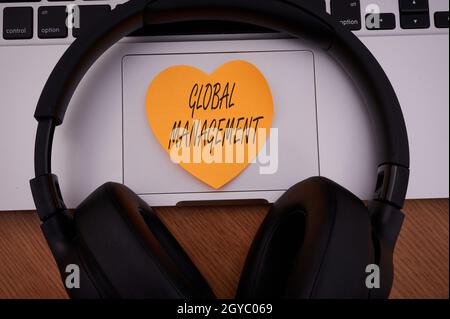 Text sign showing Global Management, Word Written on way an organization manages its business internationally Blank Notepad Laptop With Pen And Headph Stock Photo