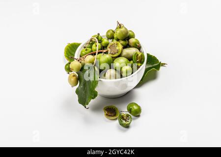 Ripe Actinidia arguta or kiwi in a bowl isolated on white background. Branches of fresh fruits with green leaves, mockup, template Stock Photo