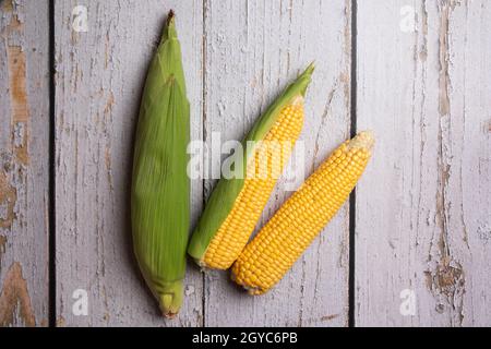 Fresh corn cobs on flat wooden background. High quality photo Stock Photo
