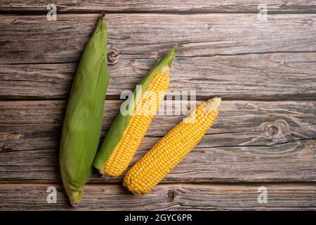 Fresh corn cobs on flat wooden background. High quality photo Stock Photo