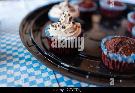 Two cupcakes and five muffins on round black plastic tray Stock Photo