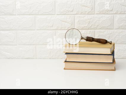 a wooden magnifying glass lies on a stack of books, new knowledge and discoveries are reading books Stock Photo
