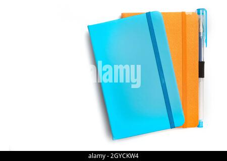 Blue and orange notebooks and a pen on a white background Stock Photo