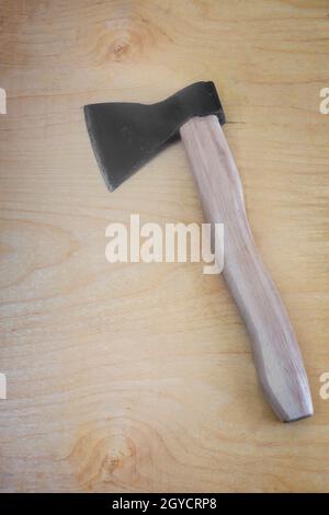 An axe with a wooden handle. A woodworking tool, a tool for chopping firewood, a sharp axe of a forester or carpenter. Top view on a wooden background Stock Photo