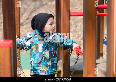 POZNAN, POLAND - Mar 25, 2018: A male toddler climbing on playground equipment in Poznan, Poland Stock Photo