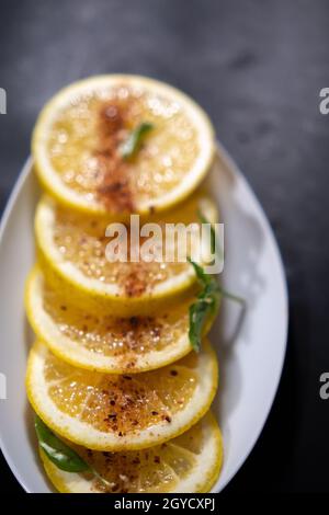 Plate of orange slices with chili powder on black surface Stock Photo
