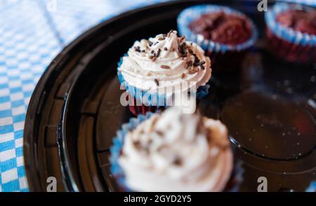 Two cupcakes and two muffins on round black plastic tray Stock Photo