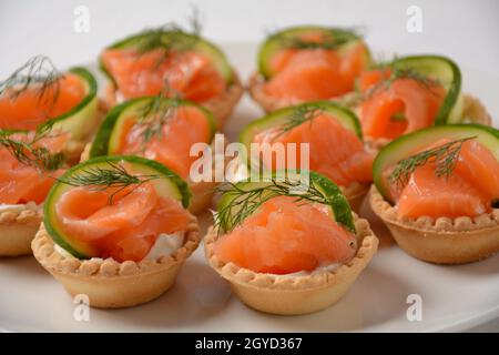 Tartlets with salmon, cheese, cucumber and dill. Tasty snacks with salted salmon and cottage cheese filling Stock Photo