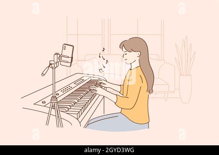 Remote distant music lesson concept. Small positive girl child sitting playing digital piano and recording video on phone during online learning and v Stock Photo