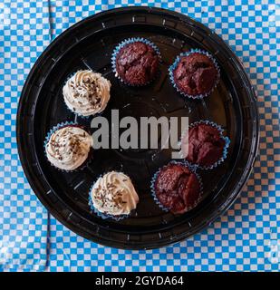 Three cupcakes and four muffins on round black plastic tray Stock Photo