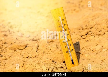 Thermometer shows very hot summer temperature in dry desert sand dunes. Climate change/global warming/desert concept. Stock Photo