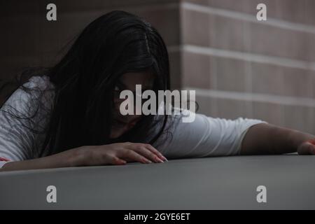 Female zombie in blood. Asian Woman ghost with blood. Horror scary fear in dark house creepy crawling move slowly creeping out. Hair covering face her Stock Photo