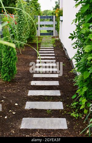 Sidewalk made from concrete blocks along the wall of a house in the garden. Stock Photo