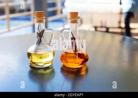 On the table are two glass bottles filled with spicy and rosemary olive oil. Close-up. Butter for pizza, rest in an Italian restaurant Stock Photo