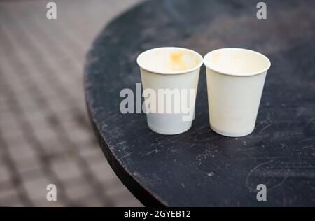 Two plastic glasses with coffee stand on the street on a wooden table. Close-up Stock Photo