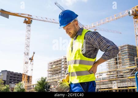 Engineer With Back Pain Injury After Accident At Construction Site Stock Photo